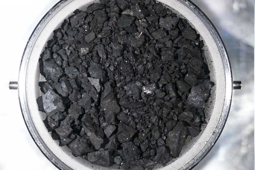An image of black rocky like material in a small metal dish. The sample is material from the surface of Asteroid Ryugu.