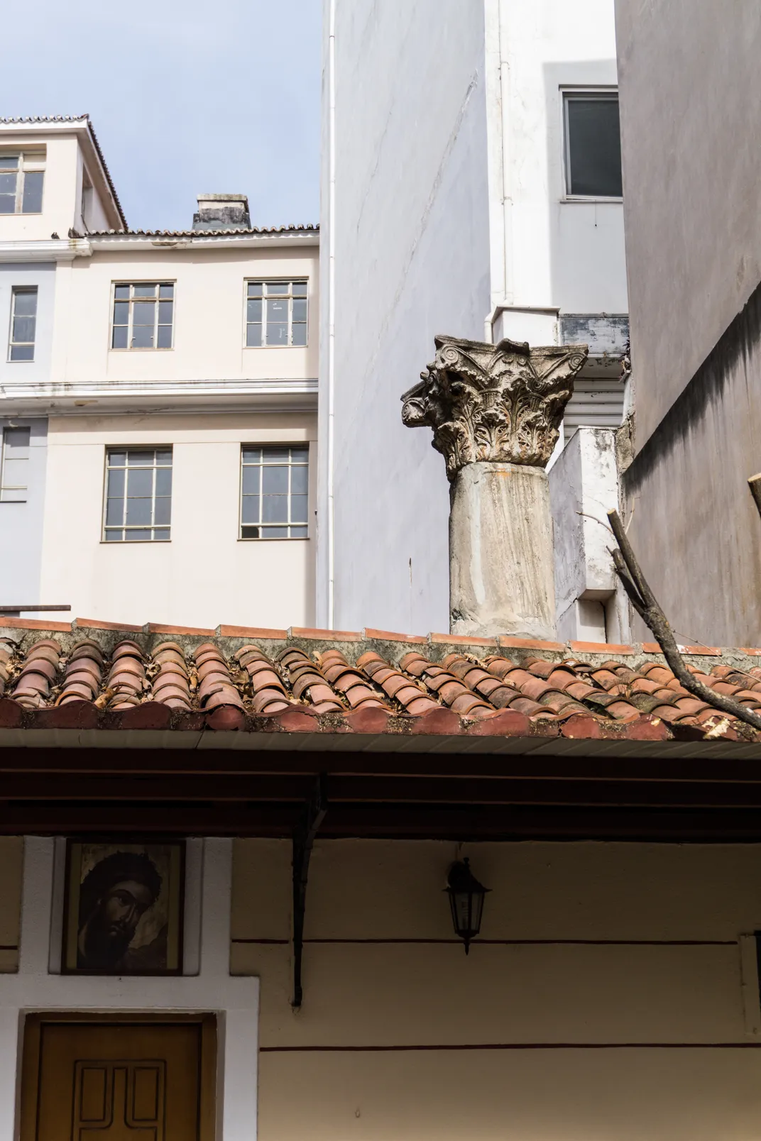 An ancient column jutting out from the roof of a building in Athens