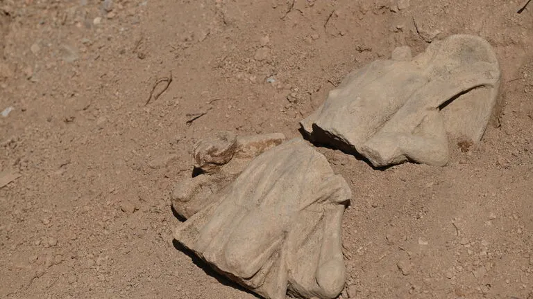 A broken statue in some dirt