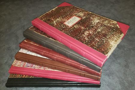 Stock books with marbled covers and leather bindings in various color fanned out.