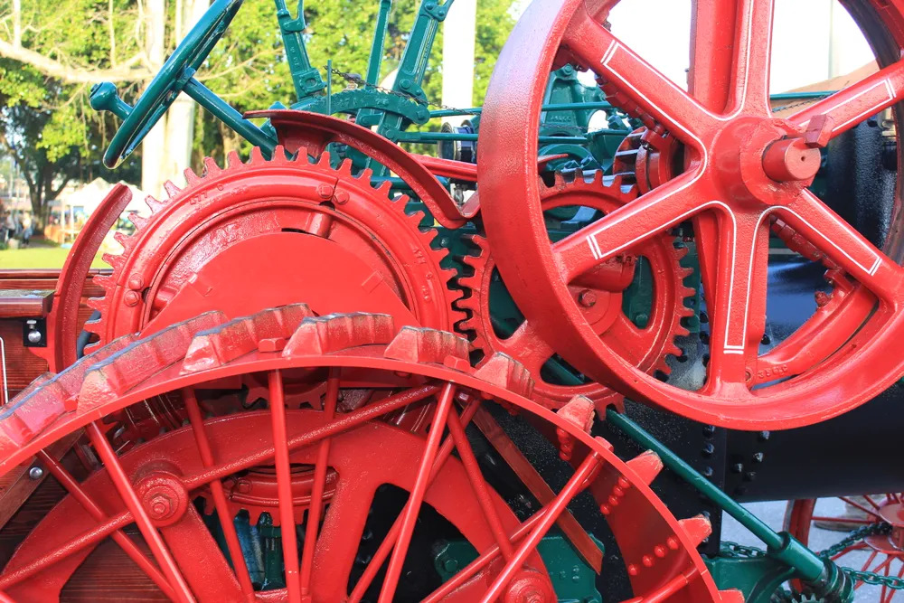 Some brightly painted intermediate gears on the side of a Case steam powered tractor and a portion of the drive wheel.