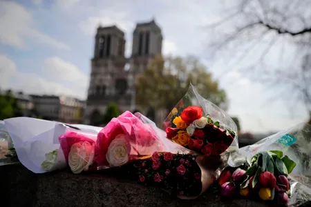 Flowers are laid on a bridge in front of the Notre-Dame-de Paris Cathedral in Paris.