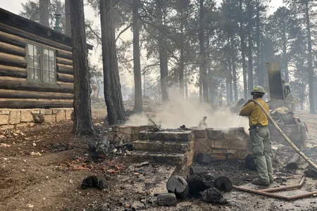 A firefighter stands beside the charred remains of a burned structure near the Grand Canyon Lodge.