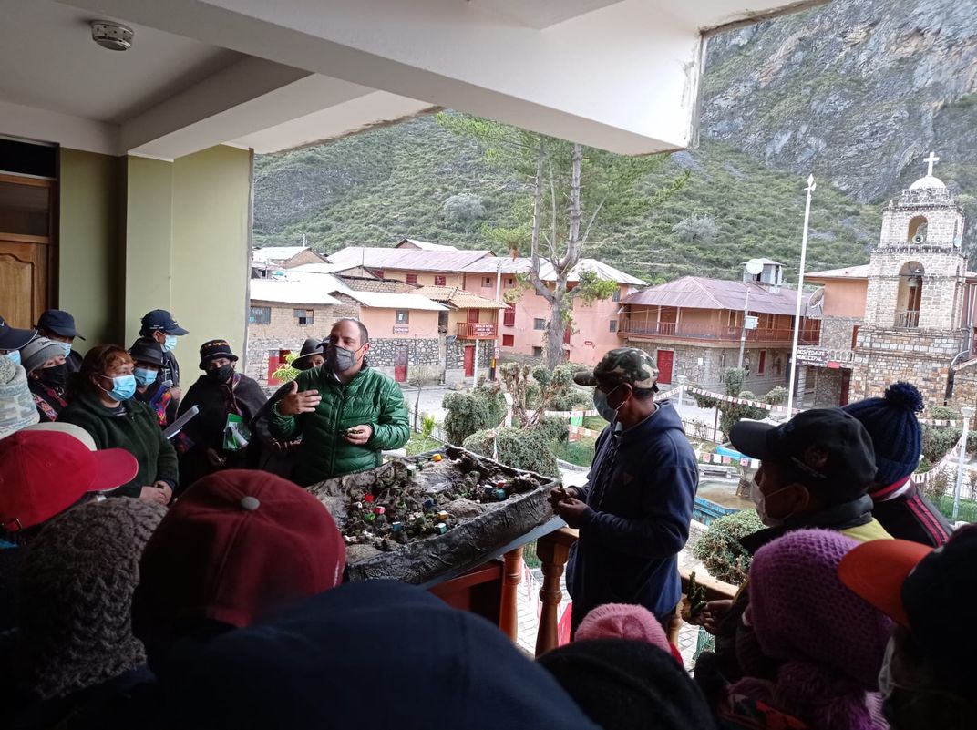 A crowd of people listen to a demonstration using a model of a watershed.