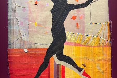A black silhouette of a jumping woman against a colorful fabric background.