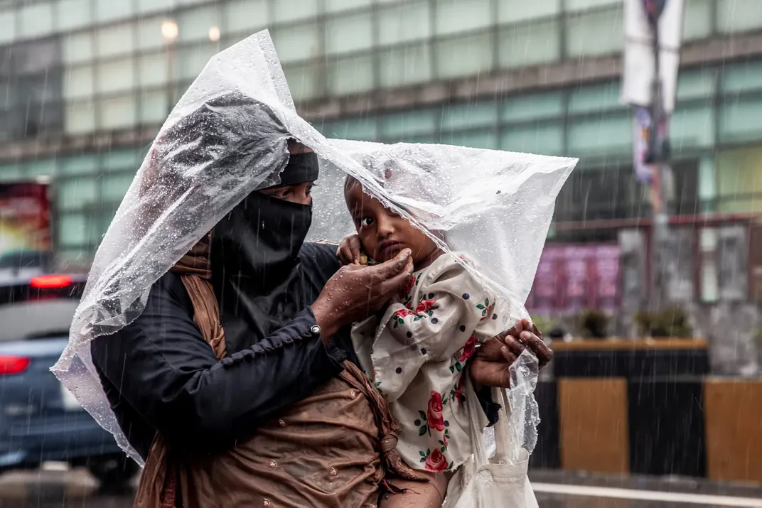 7 - Amid continuous rains in Chittagong, a woman shields her child using plastic as an umbrella.