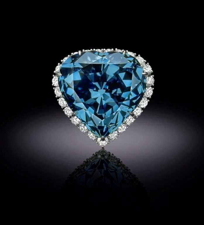 A blue, heart shaped diamond on a dark background.