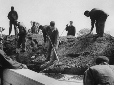 Prisoners bury a wooden coffin on Hart Island.
