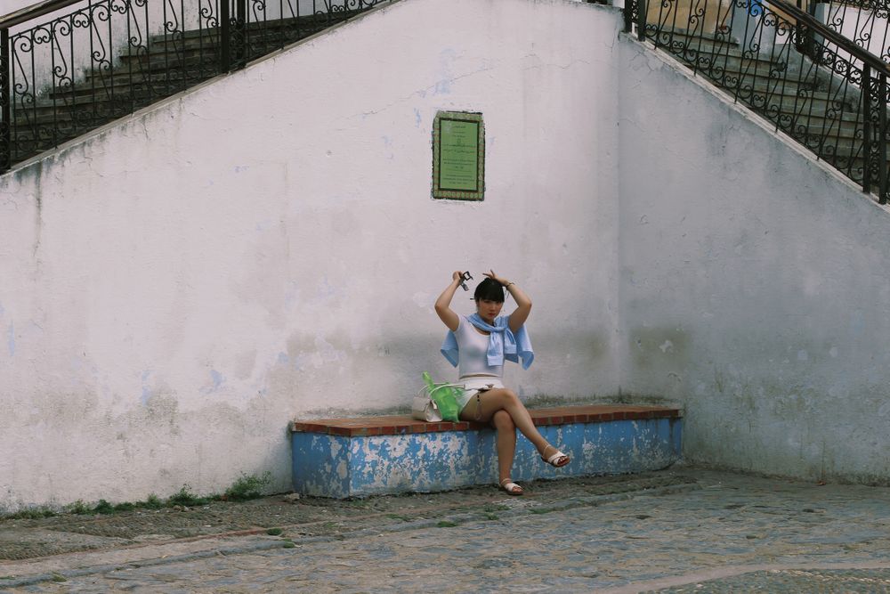 A tourist girl sits down to relax and ties her hair.