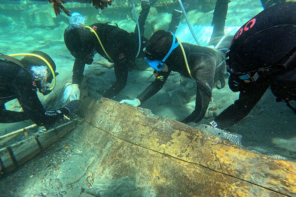 Underwater scene showing divers grabbing onto a piece of wood