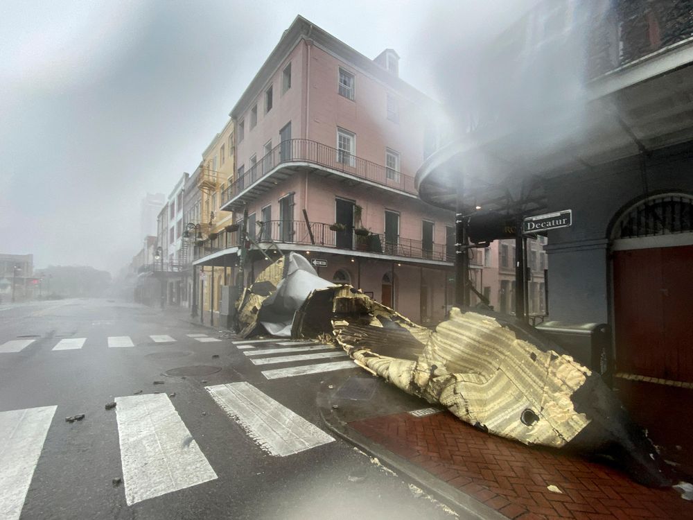 A view partially obscured by rain of a historic building at an intersection, with a part of a roof or building obstructing the entire road