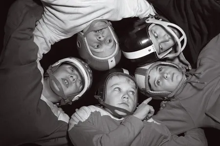 Young football players locked in a huddle in the 1960s, jealously guarding their strategy for the next play.