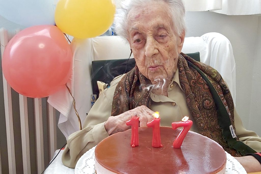 a woman blowing out candles that say "117"