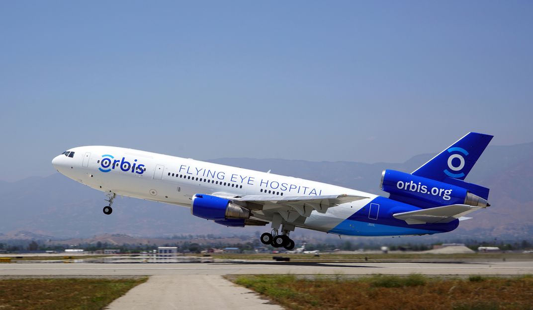 DC-10 airliner with the Orbis logo taking off from a runway.