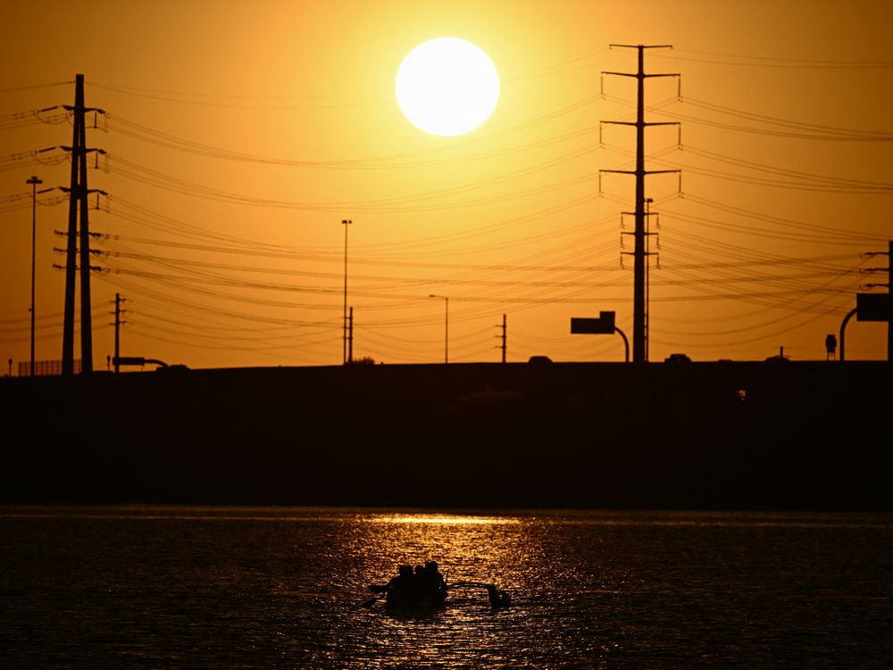 sun sets behind power lines in an orange sky