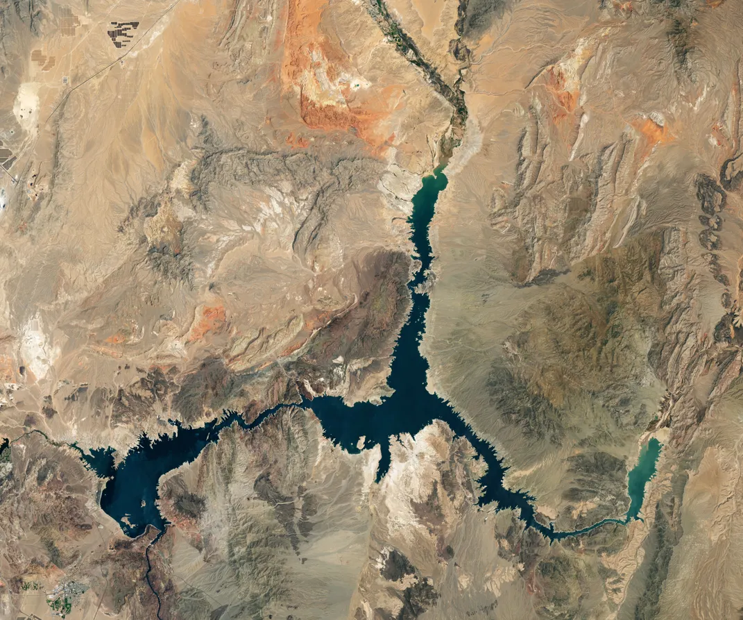 Three narrow prongs of a lake, seen from a satellite, stand out against a dry landscape