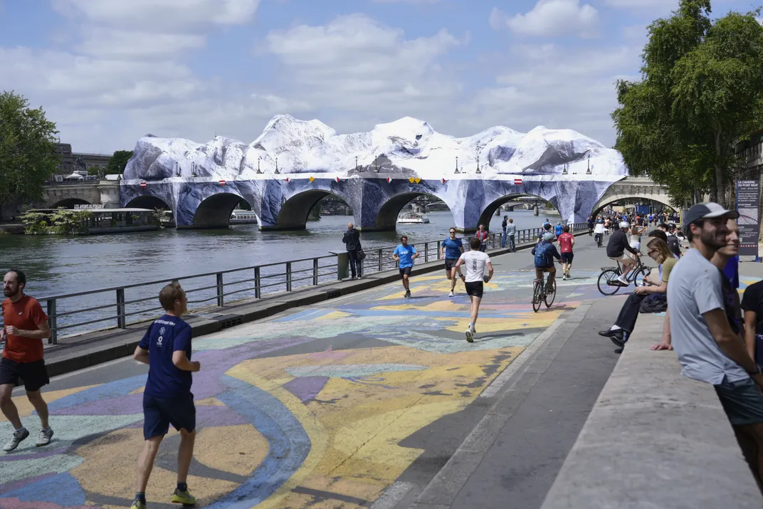 Pedestrians walking and running on the voie George Popidou with the bridge "Pont Neuf" in the background