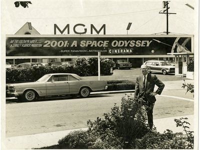 Arthur C. Clarke poses for a photo beneath a sign advertising the motion picture 