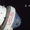 A photograph featuring the conical silver Orion spacecraft and cylindrical European Service Module in the foreground as it travels through space. In the background the Moon and then the Earth can be seen in the far distance.