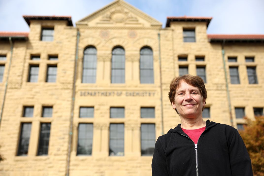 Carolyn Bertozzi poses for a photo in front of a building on Stanford University's campus.