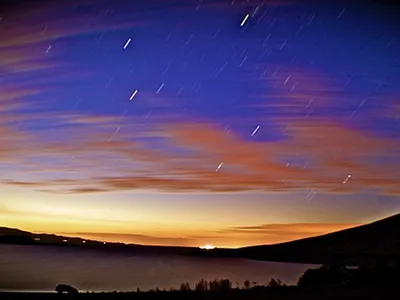 A dark sky just after dusk is set ablaze by several streaking meteorites