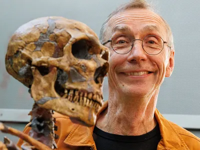 Svante P&auml;&auml;bo poses with a model of a Neanderthal skeleton after winning the 2022 Nobel Prize in Physiology or Medicine.

