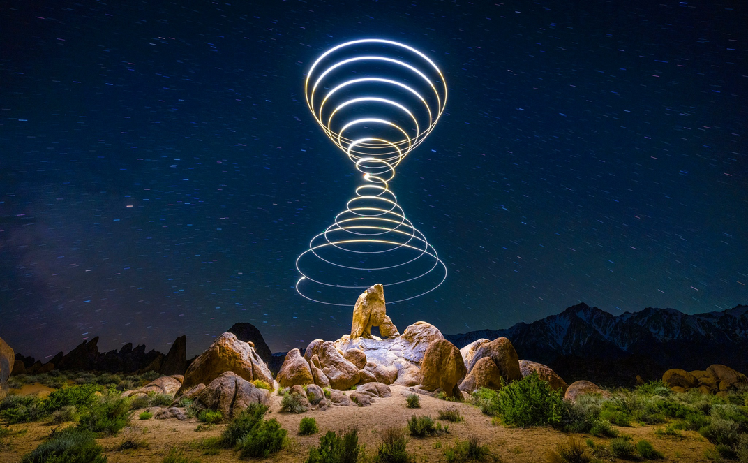 A light cone in the night sky above a rock formation