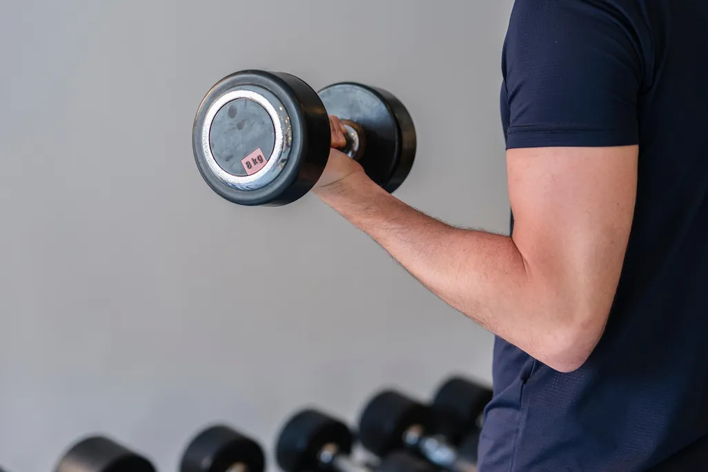 A close-up shot of a man doing a bicep curl with a small dumbbell