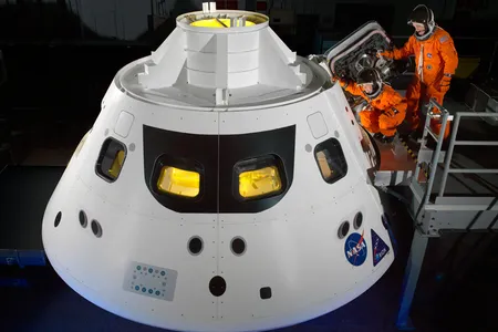 Astronauts Cady Coleman and Rick Arnold step into a mock-up of the Orion crew module at NASA's Johnson Space Center in Houston.
