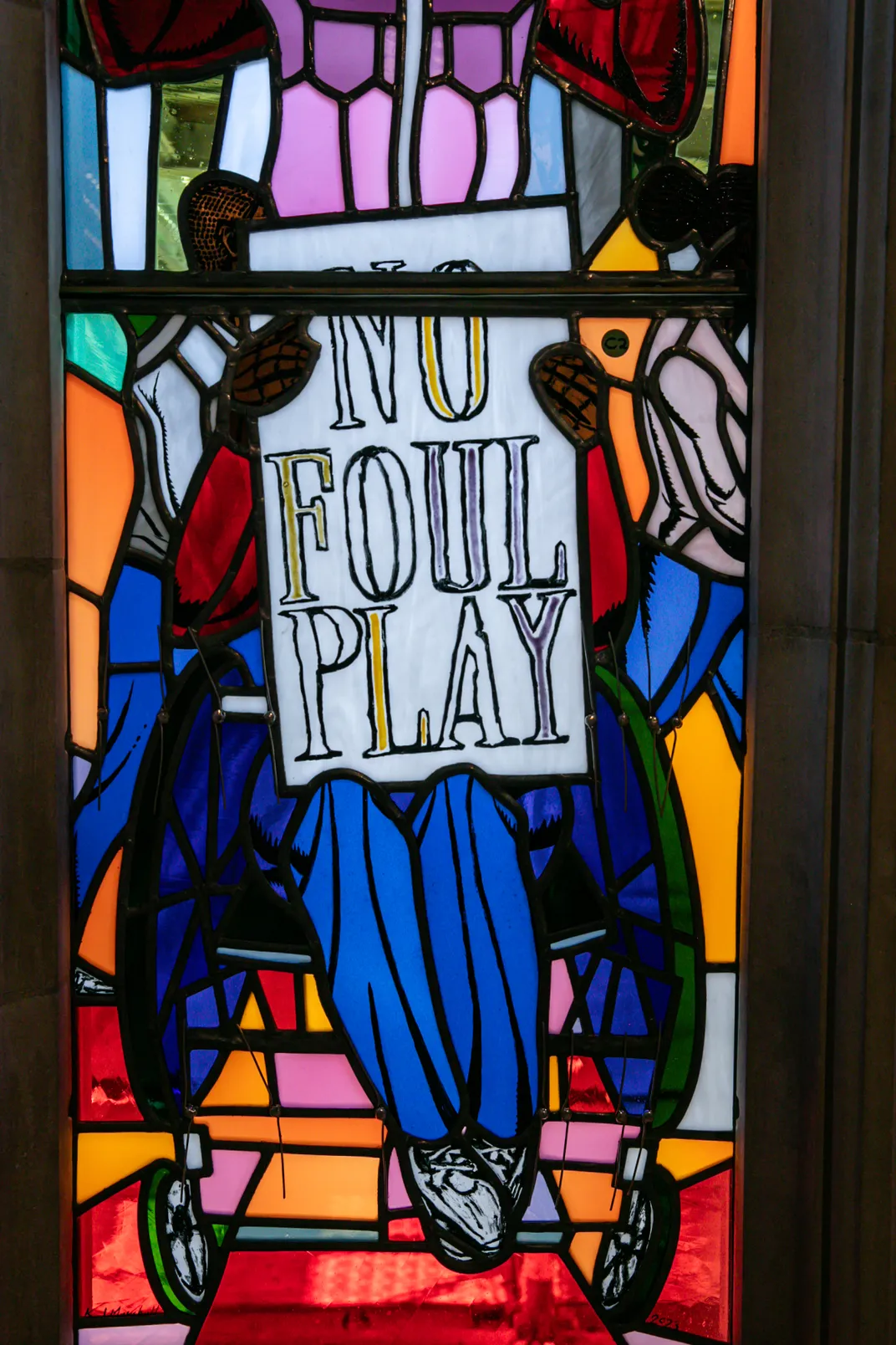 Close-up shot of stained-glass window showing protester in wheelchair holding sign