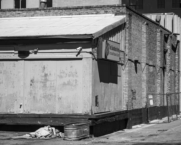 An unhoused resident of Denver, Colorado sleeps outside the Salvation Army Crossroads Center thumbnail