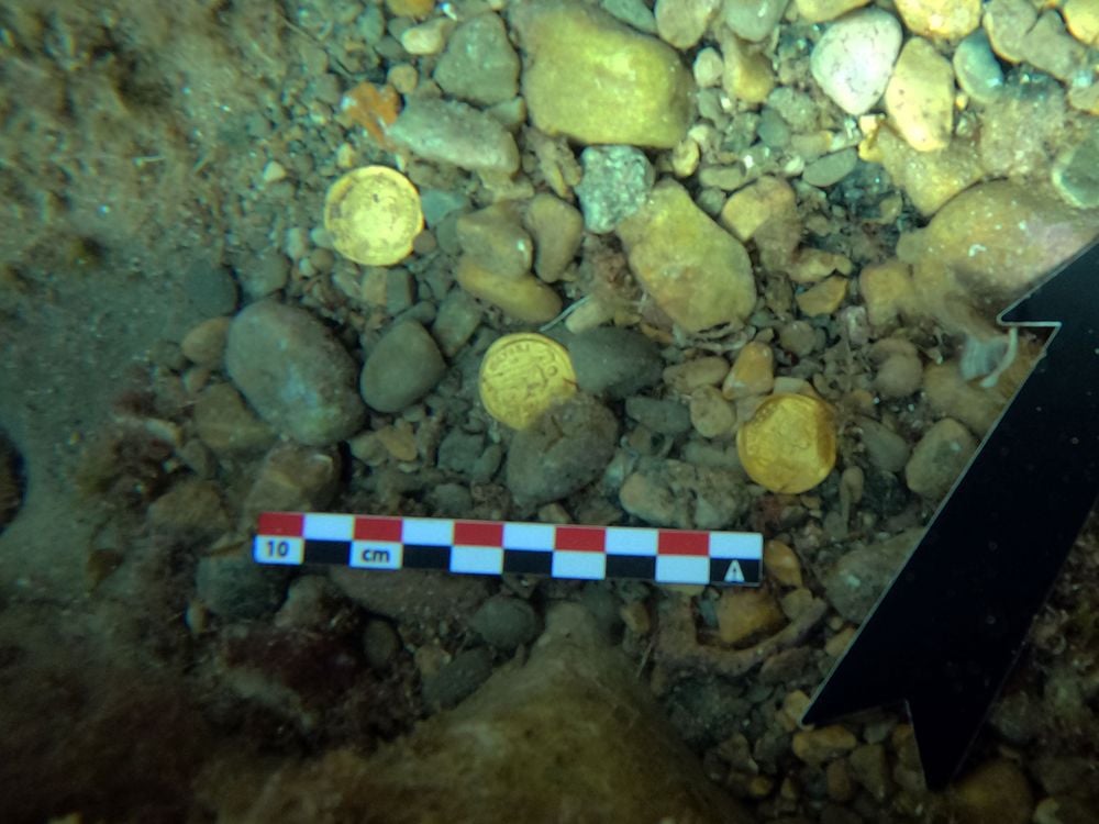 coins lying amidst small stones underwater
