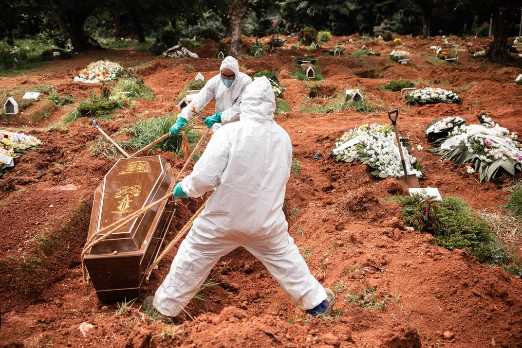 Gravediggers wearing protective suits bury a man suspected to have died of Covid-19 in the cemetery of Vila Alpina, east side of São Paulo, Brazil, in April 2020.