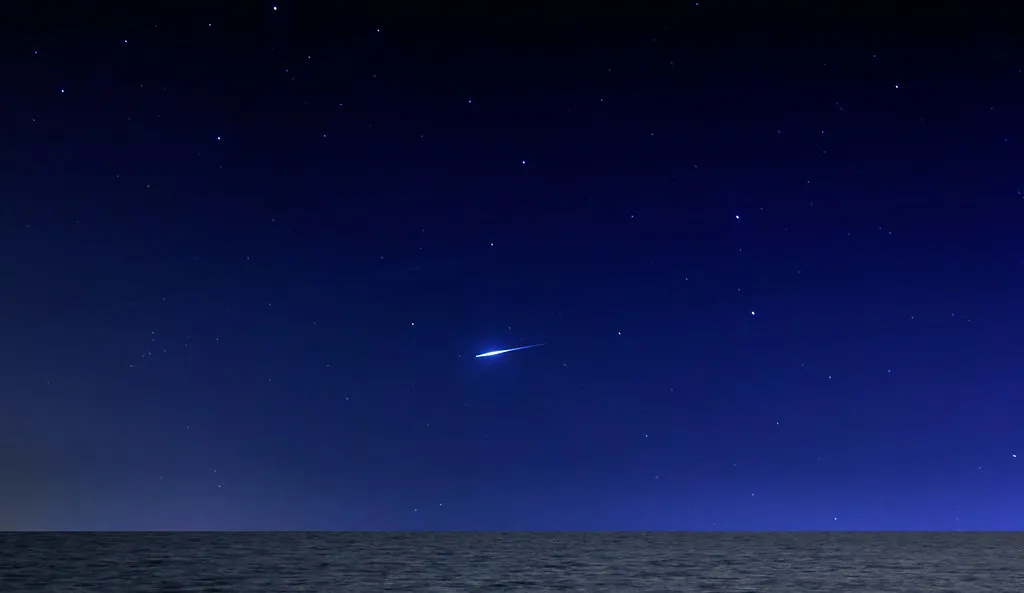 Meteor streaking across dark sky with stars
