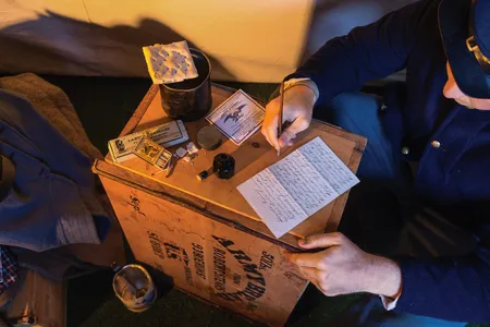 Re-enactor John Holman displays a  newly discovered letter alongside period objects including a hardtack-crate desk.