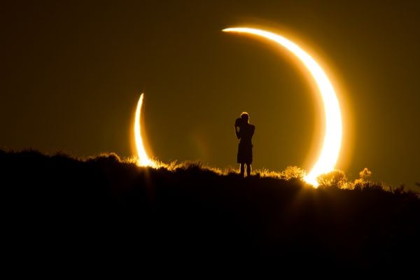 An onlooker witnesses the annular solar eclipse as the sun sets on May 20, 2012. thumbnail