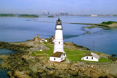 The Boston Light still shines brightly at night in Boston Harbor.