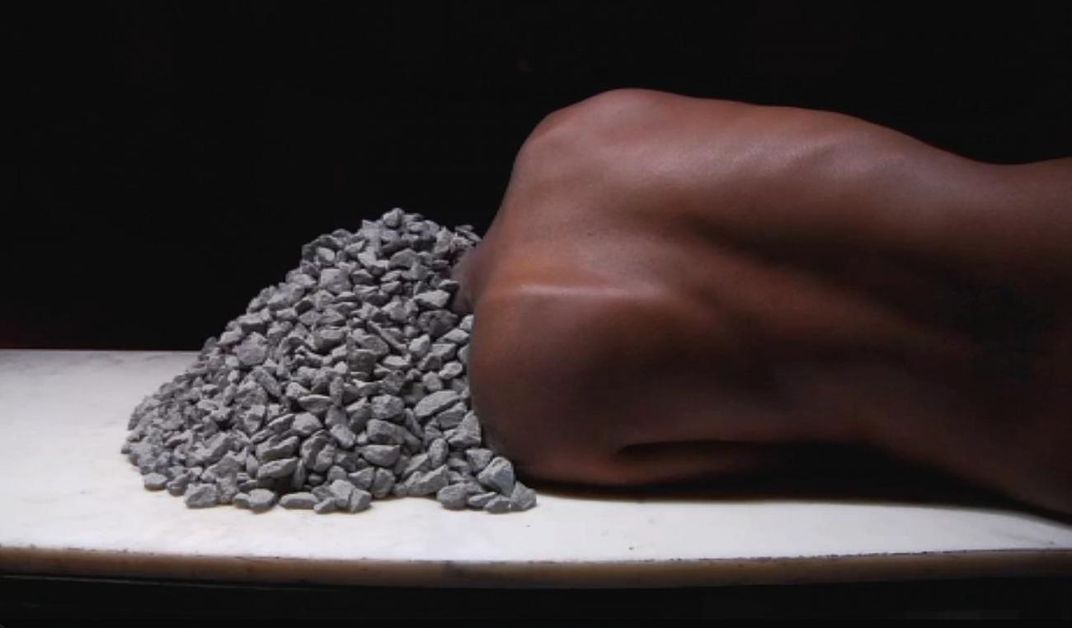 A photograph of a woman with rocks on her head