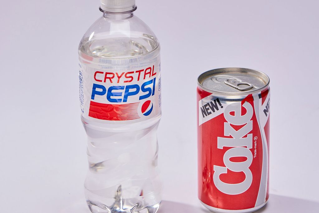 Bottle of clear Crystal Pepsi next to can of New Coke