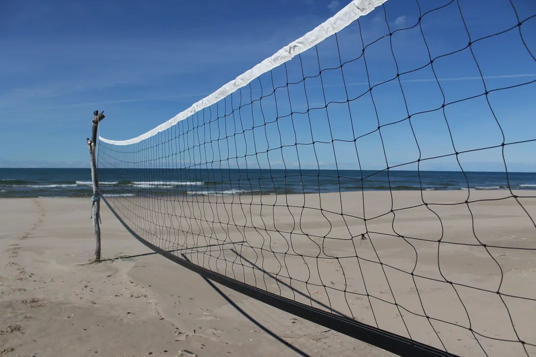 A naturally made beach volleyball net with the Lake Michigan shoreline in  the background. The beaches of Western Michigan are a source of interest  and recreation for many tourists.
