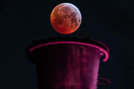 A picture taken on January 21, 2019 in Duisburg, Germany, shows a view of the Super Blood Moon above an industrial plant during a lunar eclipse.