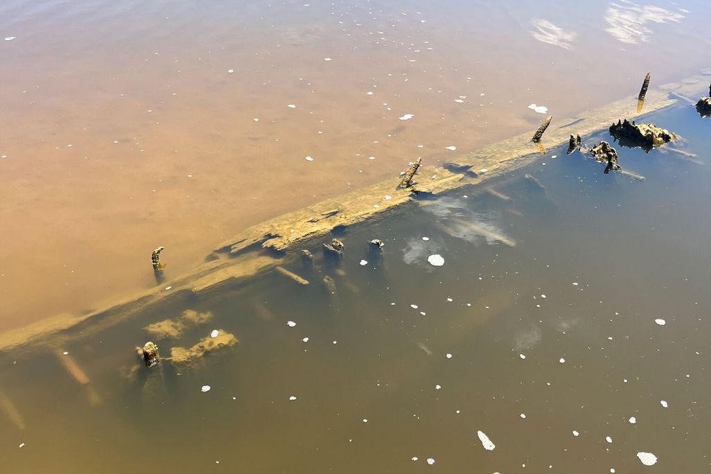 Piece of wooden shipwreck under slightly murky brown water