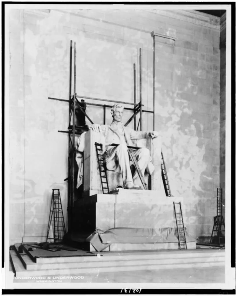 A black and white image of the Lincoln memorial, with its larger than life statue of a seated Abraham Lincoln, under construction