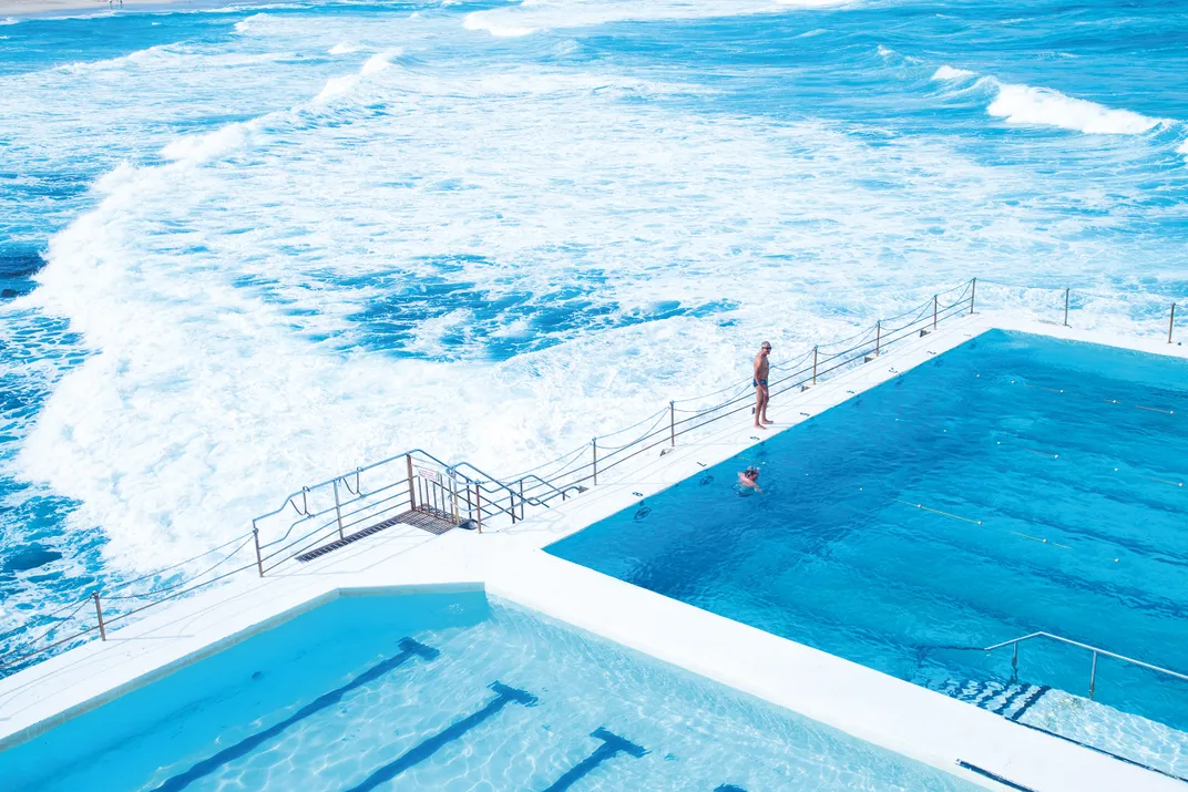 a blue pool next to the ocean