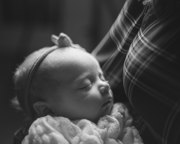 A newborn sleeping in her Mother's arms thumbnail