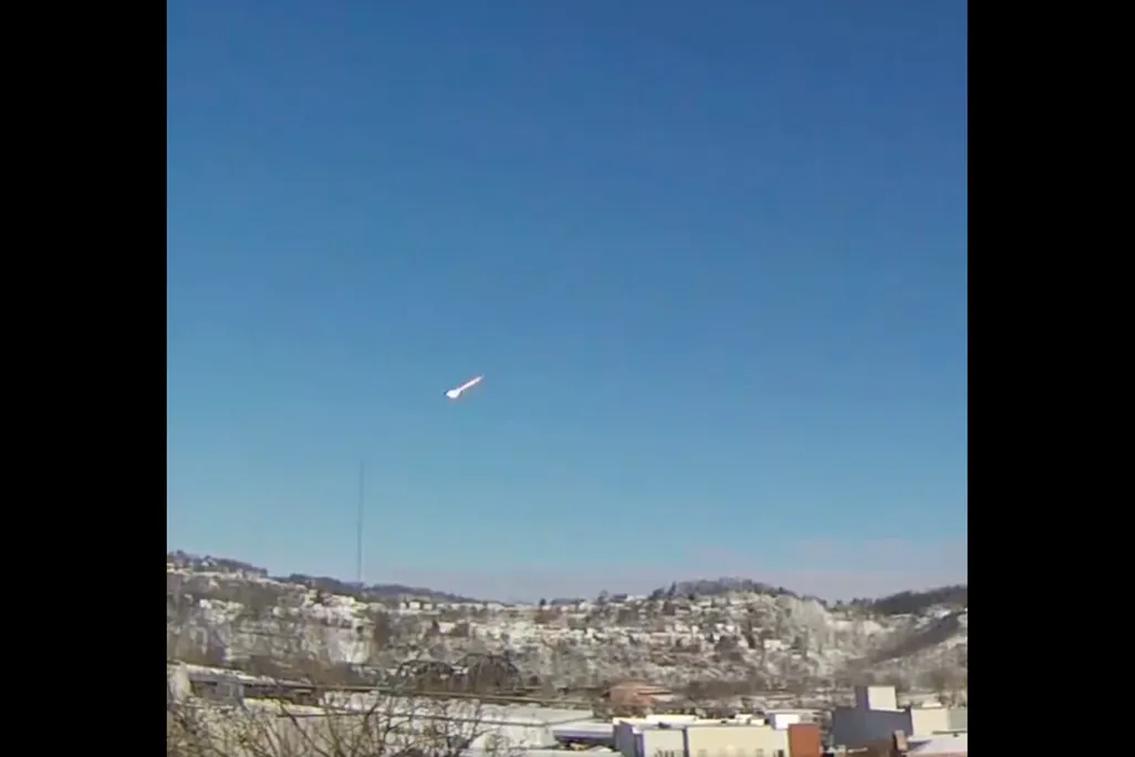 screenshot of meteor against blue sky above city