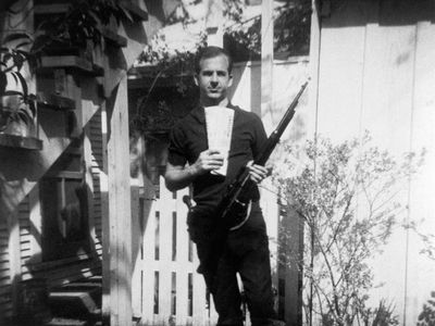 Lee Harvey Oswald stands in his backyard with Marxist newspapers and a rifle. This photo has been looked on with suspicion ever since Oswald called it a fake after John F. Kennedy's assassination in 1963.