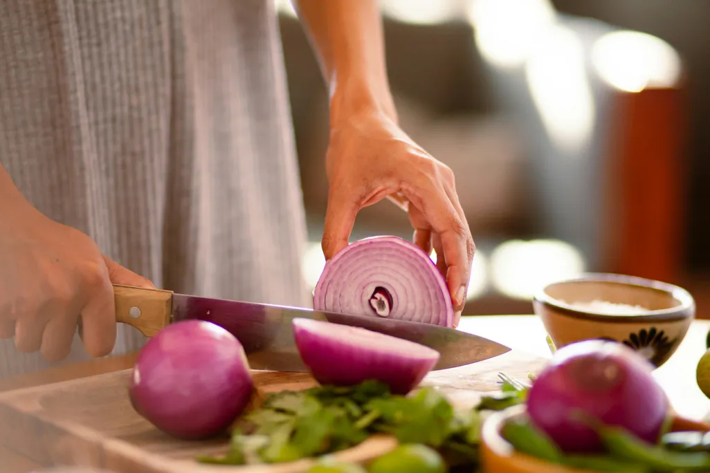 Woman's hands cutting a red onion