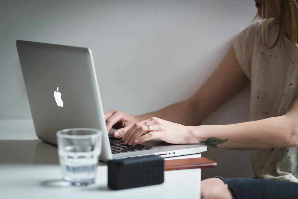 A woman typing on a laptop on a table