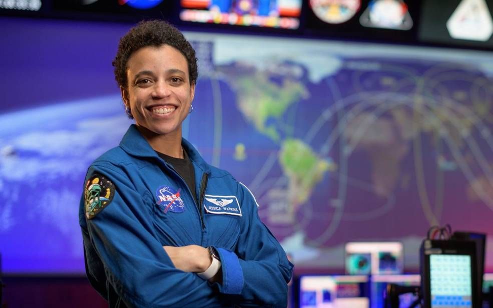 An image of Jessica Watkins, standing and smiling proudly at the camera. She has short cropped hair.